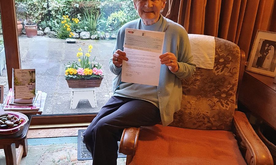 Iris Dungan holding up the letter from President Higgins to mark her 100th birthday this year