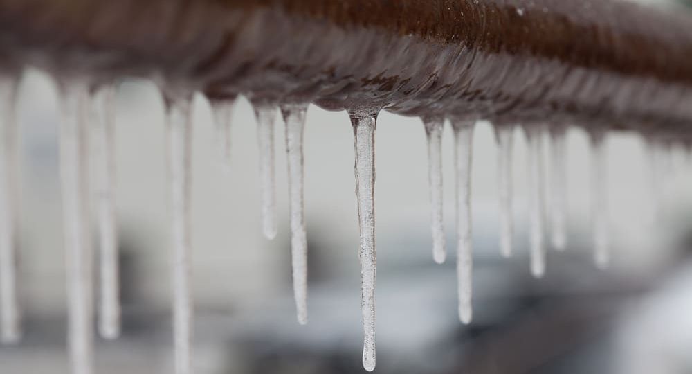 Icicles,Hanging,From,A,Brown,Pipe.,Frozen,Water,And,Metal